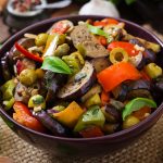 Hot spicy stew eggplant, sweet pepper, olives and capers with basil leaves.