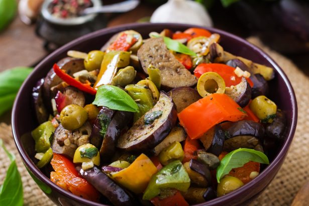 Hot spicy stew eggplant, sweet pepper, olives and capers with basil leaves.